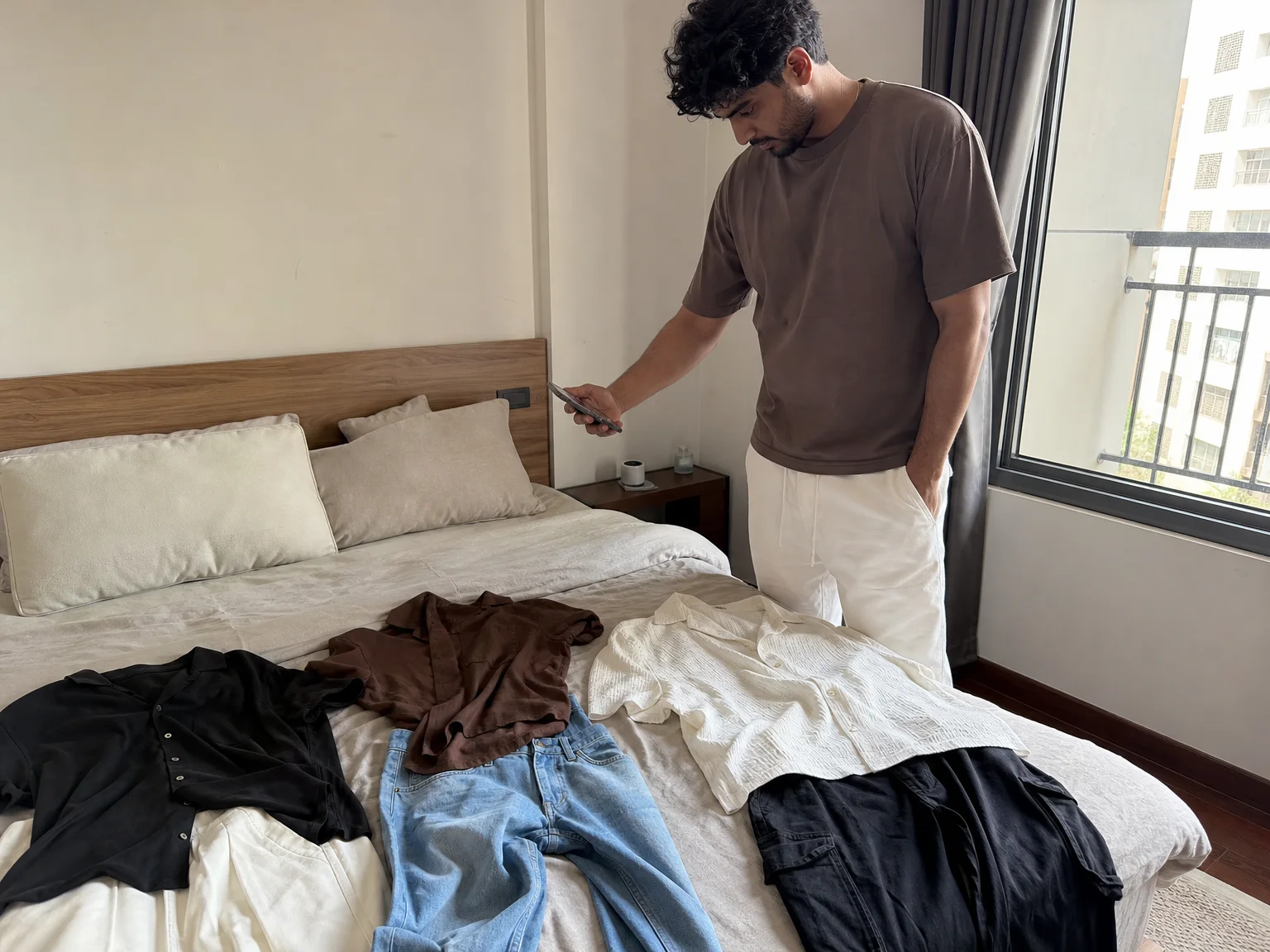 A man comparing three outfit options laid out on his bed before planning a sponsored photo