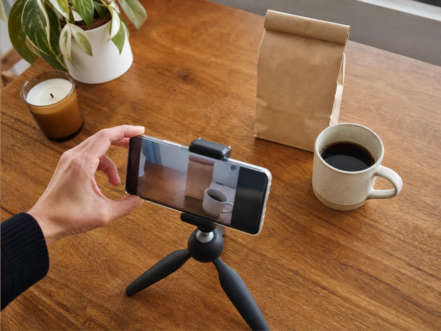 An overhead view of a phone mounted on a mini tripod filming a coffee setup on a table