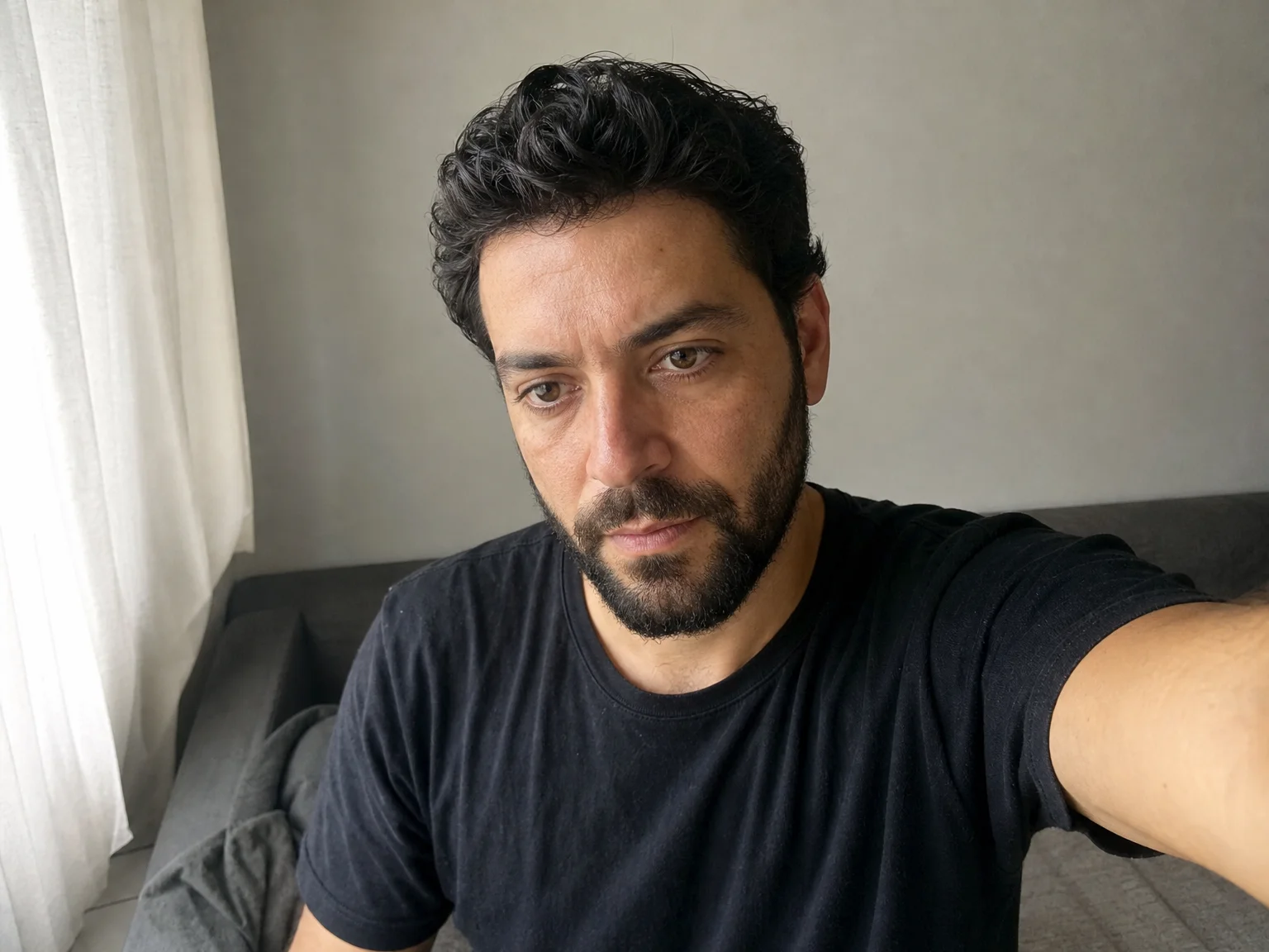Over-the-shoulder view of a man holding his phone slightly above eye level with the camera angled down toward his face